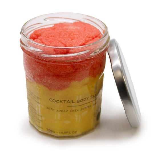 Zuckerkörperpeeling mit Pfirsich-Sangria-Duft, Peeling-Kristalle in rotorange und gelber Farbgebung, in durchsichtigem Behälter mit silberfarbenen Deckel, der abgeschraubt an das Glas gelehnt steht.