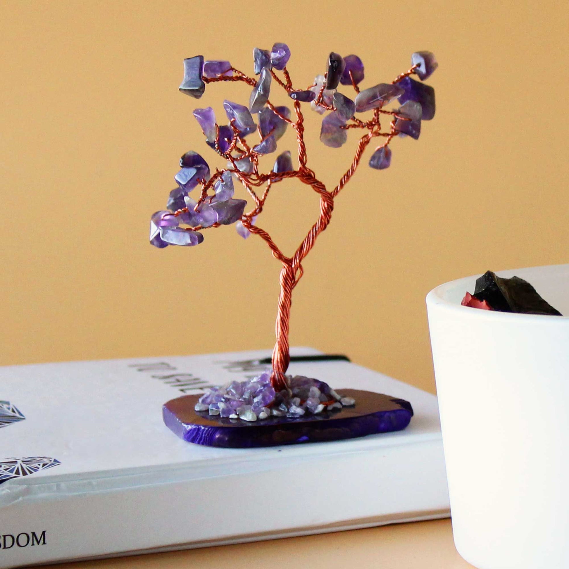 Edelsteinbaum Amethyst auf Achatbasis – auf Buch stehend, Dekoration im Hintergrund